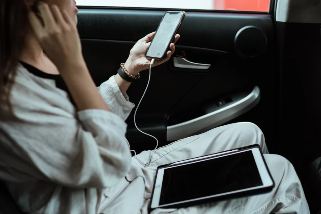 Girl passenger in rear car seat using iphone & ipad