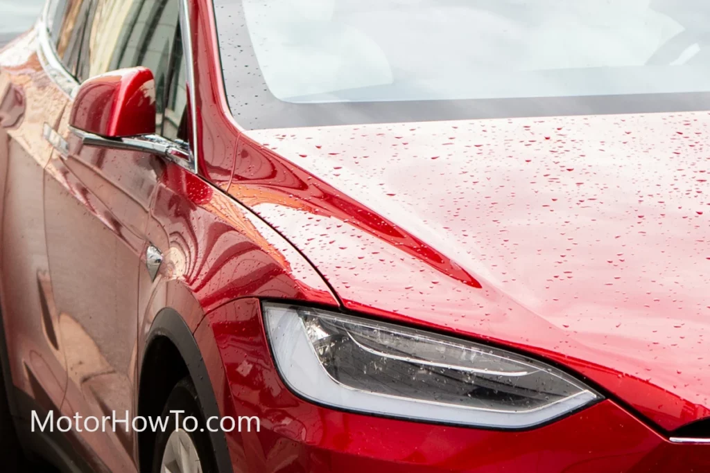 Red electric car getting wet in rain