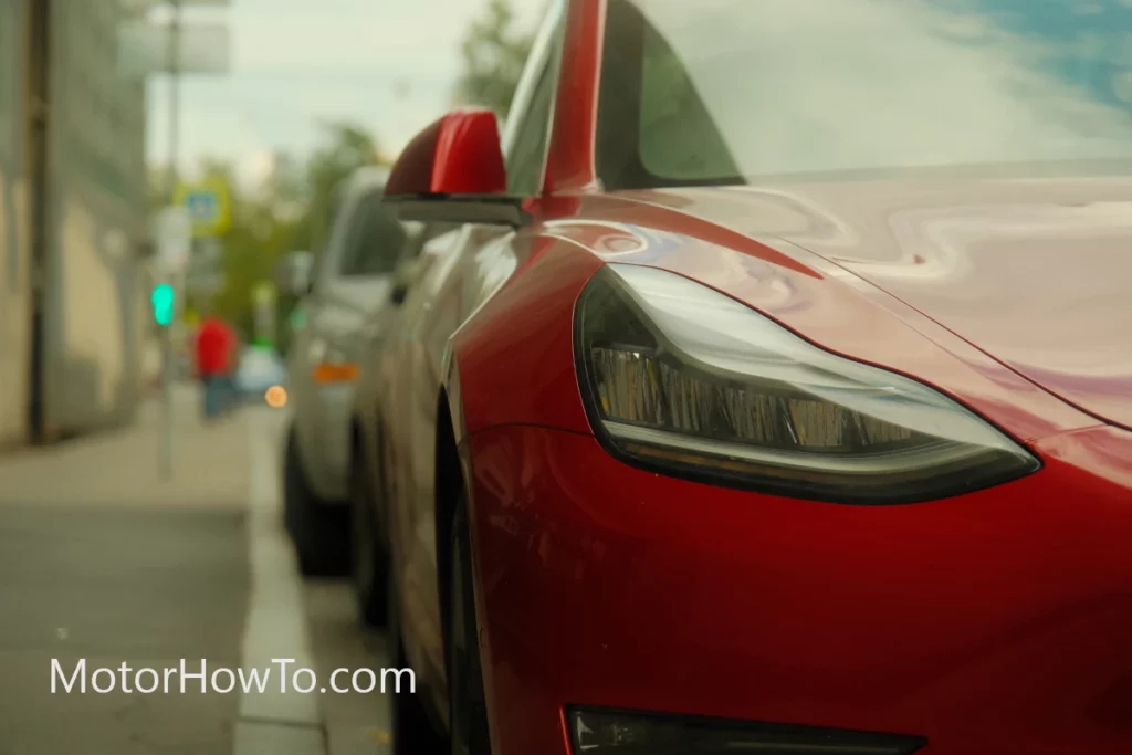 Red Tesla parked along the roadside
