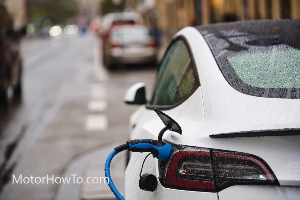 White electric car charging in rain near charging station